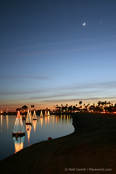 Lights in the form of trees floating on bay with crescent moon and Venus in sky - photographer Matt Carroll