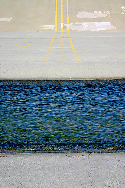 water flowing over concrete with yellow stripes painted on it